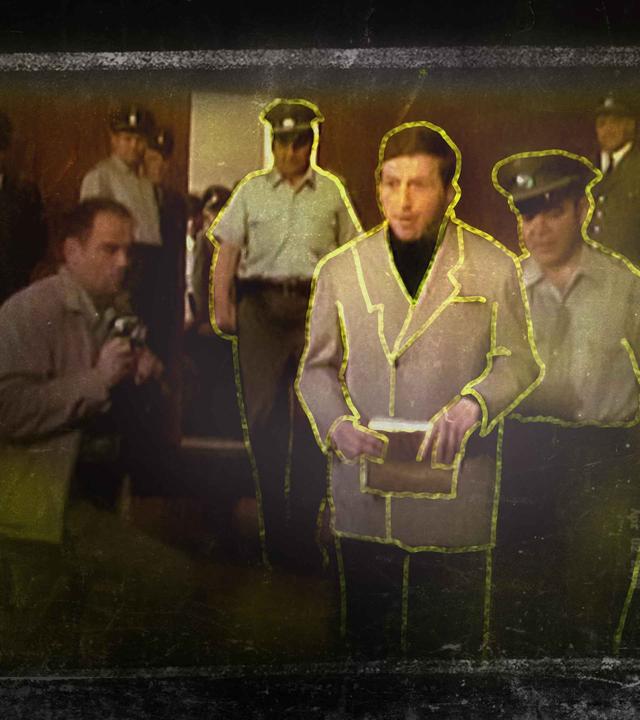 Ein gelb markierter Mann mit Zetteln in der Hand, im Hintergrund uniformierte Männer und ein Reporter