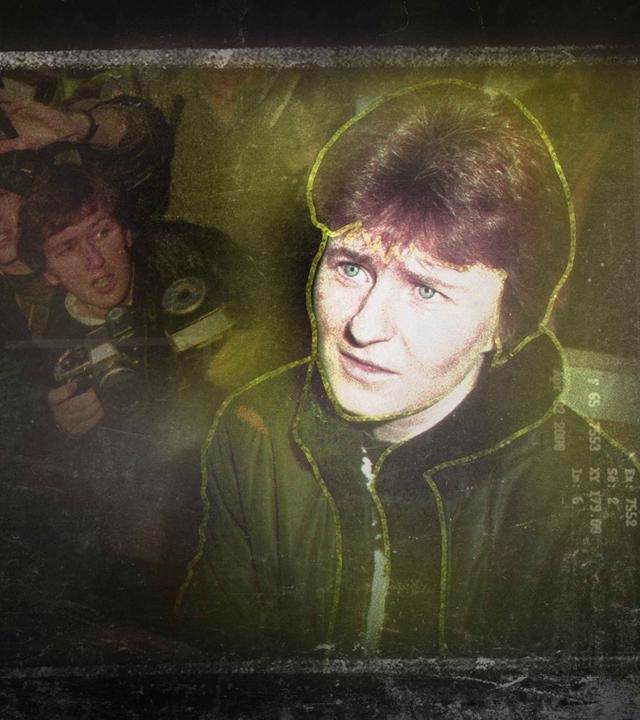 Eine Frau mit kurzen Haaren und hellen Augen, im Hintergrund Reporter mit großen Kameras