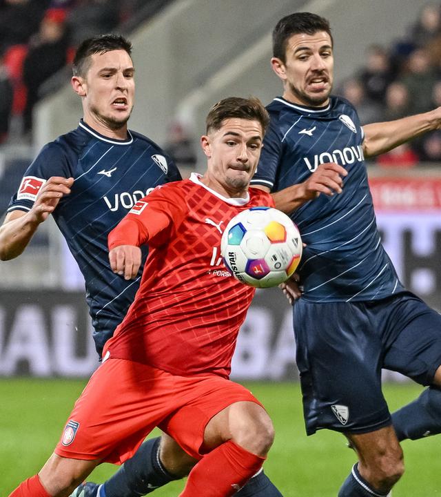 Bochums Keven Schlotterbeck (l) und Bochums Anthony Losilla (r) in Aktion gegen Heidenheims Nikola Dovedan (M). 