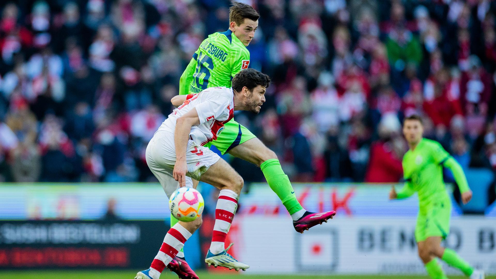 25.02.2023, Nordrhein-Westfalen, Köln: Fußball: Bundesliga, 1. FC Köln - VfL Wolfsburg, 22. Spieltag, RheinEnergieStadion. Kölns Jonas Hector (l) und Wolfsburgs Jakub Kaminski versuchen an den Ball zu kommen. 