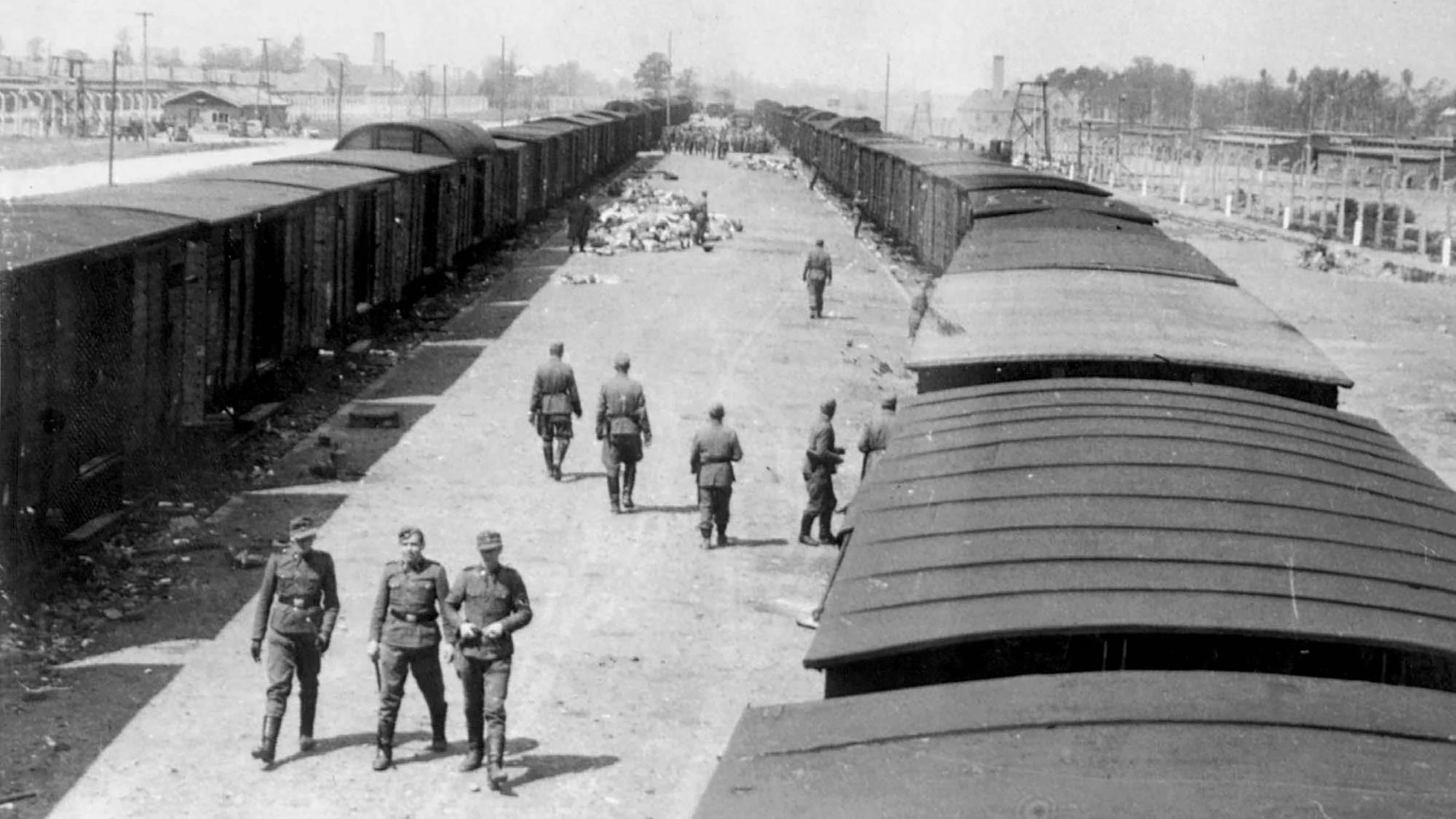 KZ Auschwitz-Birkenau - Der SS-Fotograf Bernhard Walter geht über die noch verschlossenen Waggons, im denen die Juden aus Tacovo warten. 