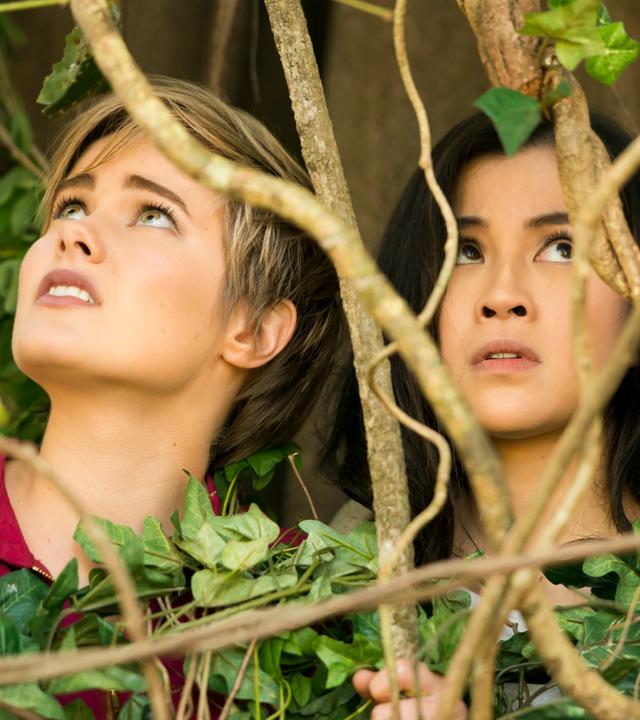 Imogen und Kyra sitzen in einem Gebüsch.