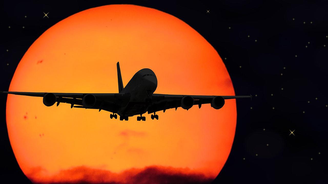 Bild eines im Sonnenuntergang fliegenden Flugzeug