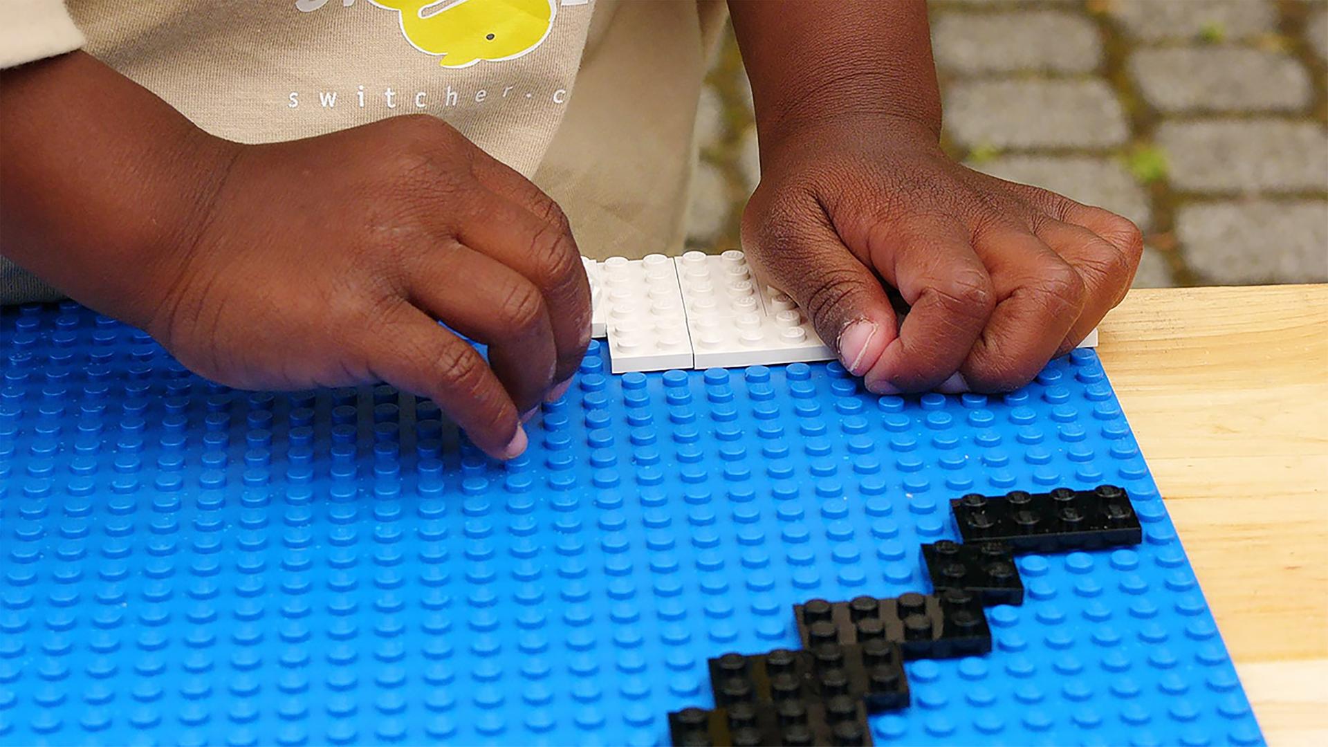 Detailaufnahme von den Händen eines Kindes beim Lego-Spiel