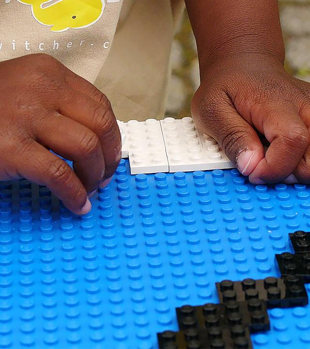 Detailaufnahme von den Händen eines Kindes beim Lego-Spiel