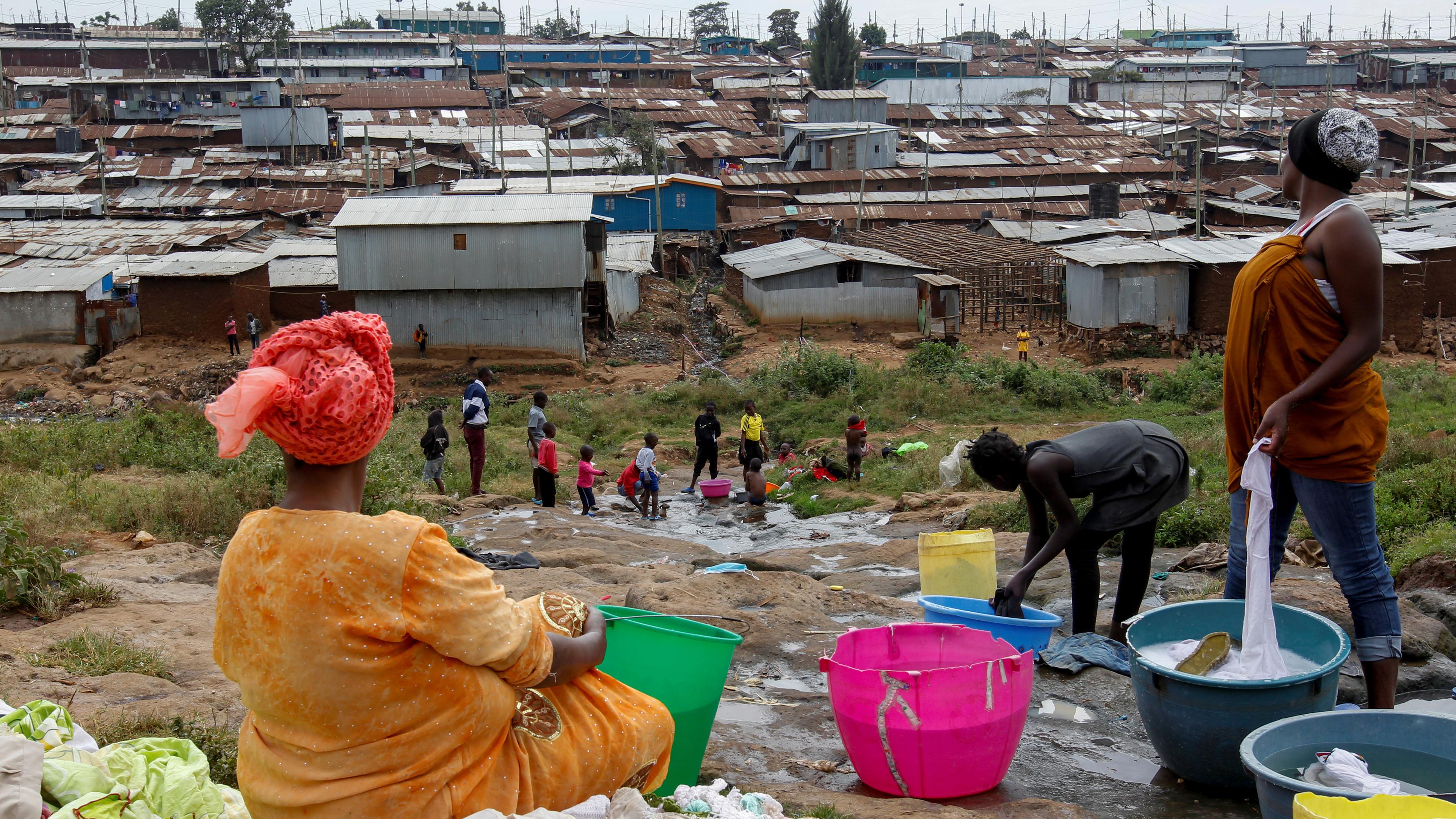 Zwei Frauen waschen Wäsche in einem Slum