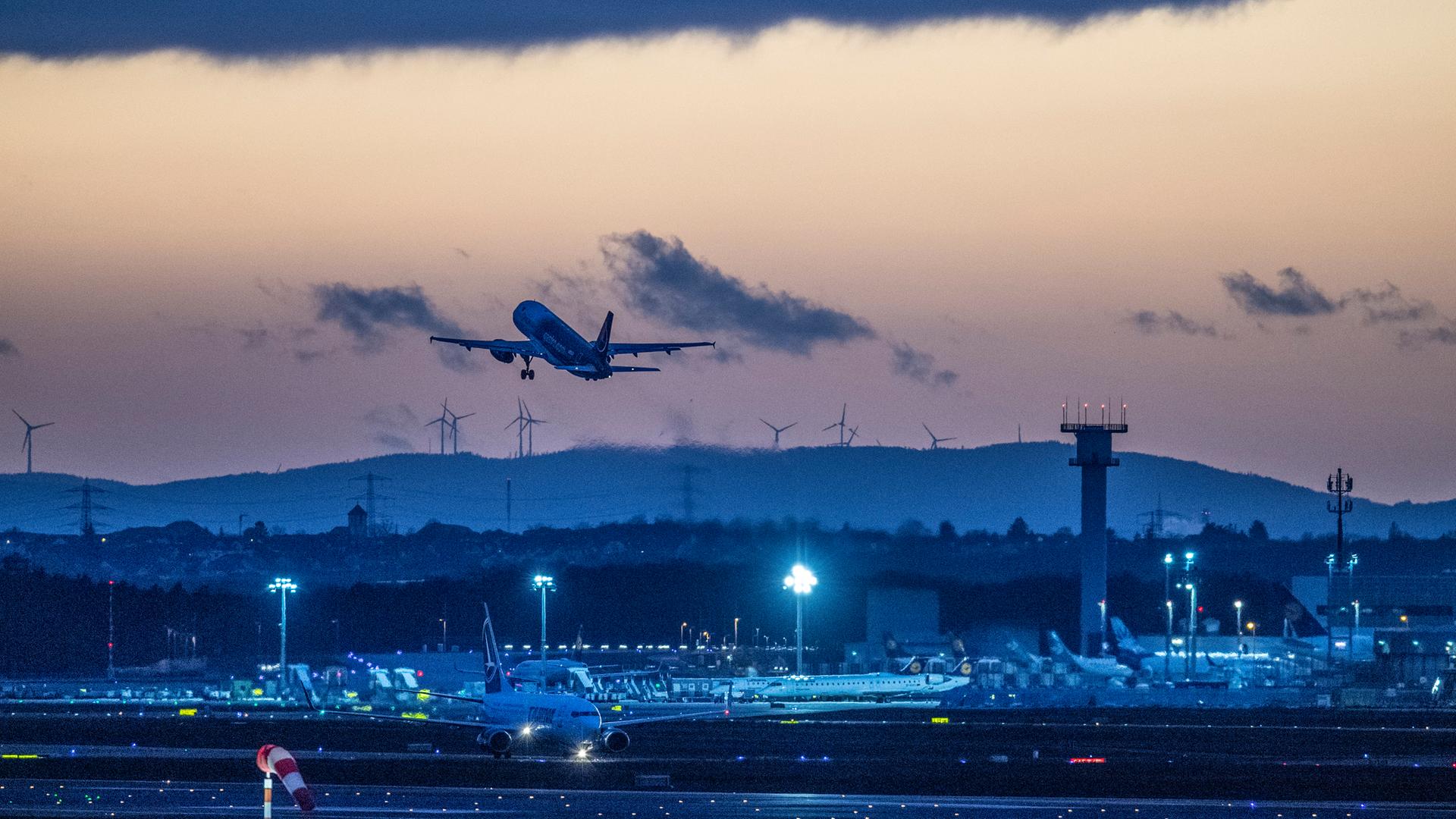 Eine Passagiermaschien startet nach Sonnenuntergang vom Flughafen Frankfurt