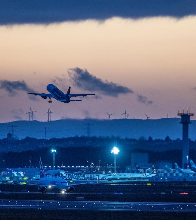 Eine Passagiermaschien startet nach Sonnenuntergang vom Flughafen Frankfurt