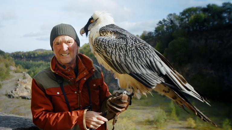 "Kielings wilde Welt - Vogelparadiese": Andreas Kieling steht mit einem Bartgeier auf dem Arm in einem Steinbruch.