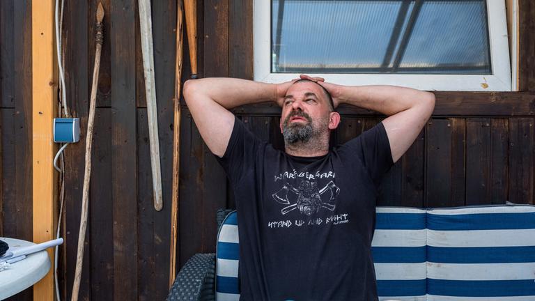 "Im Kopf geht der Krieg weiter - Überleben nach dem Einsatz": Martin sitzt draußen auf einer Bank und hat die Hände hinter dem Kopf verschränkt.