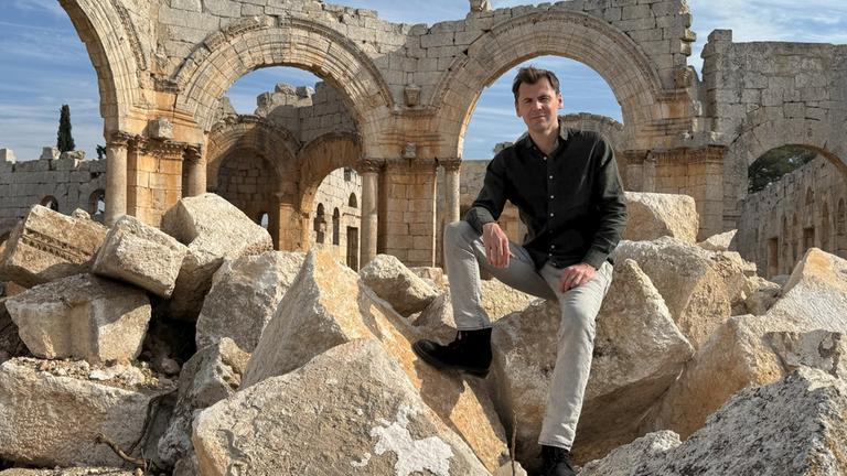 "Terra X: Die letzten Geheimnisse des Orients- Rückkehr nach Syrien": Daniel Gerlach sitzt auf antiken Blöcken in der Ruine des Simeonsklosters in Nordsyrien.