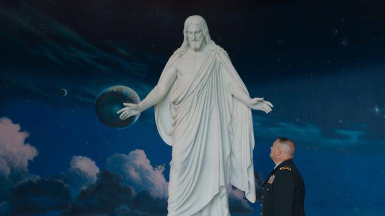 The Gate - Ein Leben lang im Krieg: US-Soldat steht vor großer Jesus Statue.