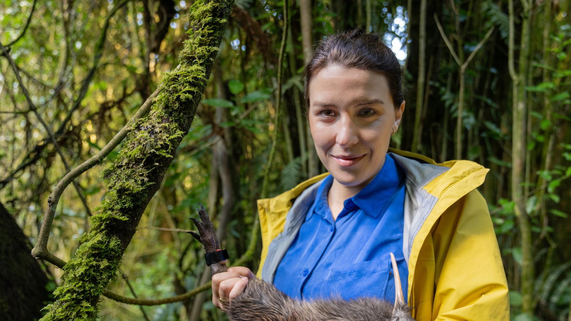 "Faszination Erde - mit Hannah Emde - Neuseeland - Lizenz zum Töten": Hannah Emde steht im Grünen und hält ein Kiwi auf dem Arm. Sie schaut lächelnd in die Kamera.