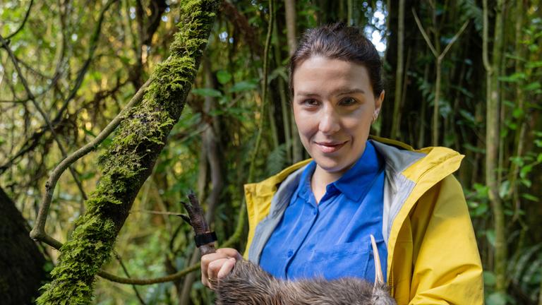 "Faszination Erde - mit Hannah Emde - Neuseeland - Lizenz zum Töten": Hannah Emde steht im Grünen und hält ein Kiwi auf dem Arm. Sie schaut lächelnd in die Kamera.