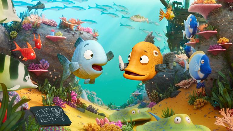 "Flunkerfisch": Im Meer auf dem Meeresgrund: Flori Flunkerfisch befindet sich neben seinem Freund Peter. Er lacht diesen mit begeistertem Gesichtsausdruck an. Dieser schaut etwas skeptisch. Um sie herum ist die wunderschöne, bunte Unterwasserwelt mit bunten Fischen und Pflanzen.