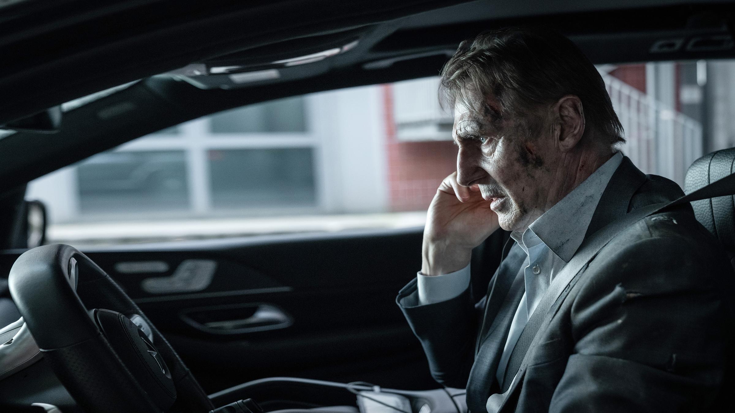 "Retribution - Vergeltung": Nahaufnahme: Matt (Liam Neeson) sitzt mit verschmutztem Gesicht und angespanntem Blick im Auto am Steuer.