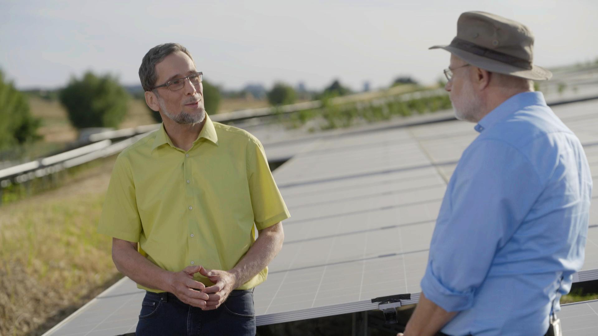 "Terra X Harald Lesch: Freundliches Klima - so kriegen wir's hin": Harald Lesch und Prof. Volker Quaschning stehen im Freien vor riesigen Solarpaneelen und unterhalten sich.