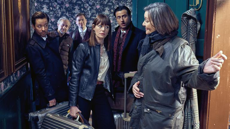 "Der Pfau": Lady McIntosh (Victoria Carling) führt die Gruppe, bestehend aus Linda (Lavinia Wilson), Bernhard (Serkan Kaya), David (David Kross), Jim (Jürgen Vogel) und Andreas(Tom Schilling), mit einer einladenden Handbewegung und einem Lächeln auf den Lippen durch eine große, alte Holztür in ihr Zimmer. Die Gruppe betritt mit Koffern und skeptischen Blicken den Raum.