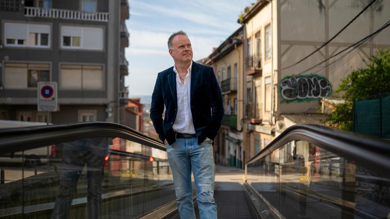 "Am Puls mit Christian Sievers - Wie retten wir unsere Städte? – Leben statt Leere": Christian Sievers steht auf einer Rolltreppe in der Innenstadt von Santander und schaut zur Seite.