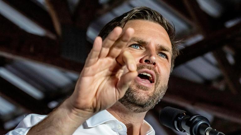 "Trumps Mann fürs Grobe - Wie viel Macht hat J.D. Vance?": Porträtaufnahme aus Untersicht: JD Vance spricht in ein Mikrofon und gestikuliert mit der rechten Hand.