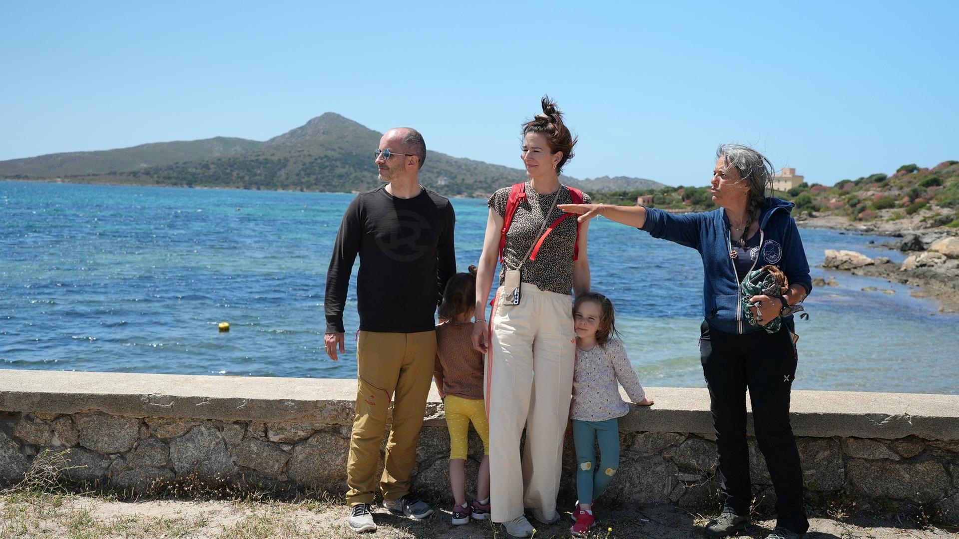 lan b: Bewusst unterwegs - Nachhaltiger in den Urlaub": Eine Familie mit zwei Kleinkindern steht neben Tourguide Giuliana Atzori am befestigten Ufer. Giuliana Atzori zeigt zur Seite, alle schauen in diese Richtung.