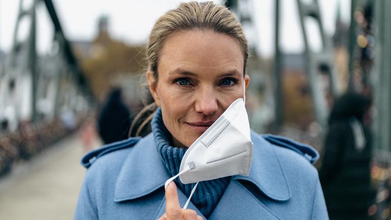"Am Puls mit Sarah Tacke - Meine offene Rechnung mit Corona": Porträtaufnahme: Sarah Tacke schaut in die Kamera und setzt eine Corona-Maske ab.