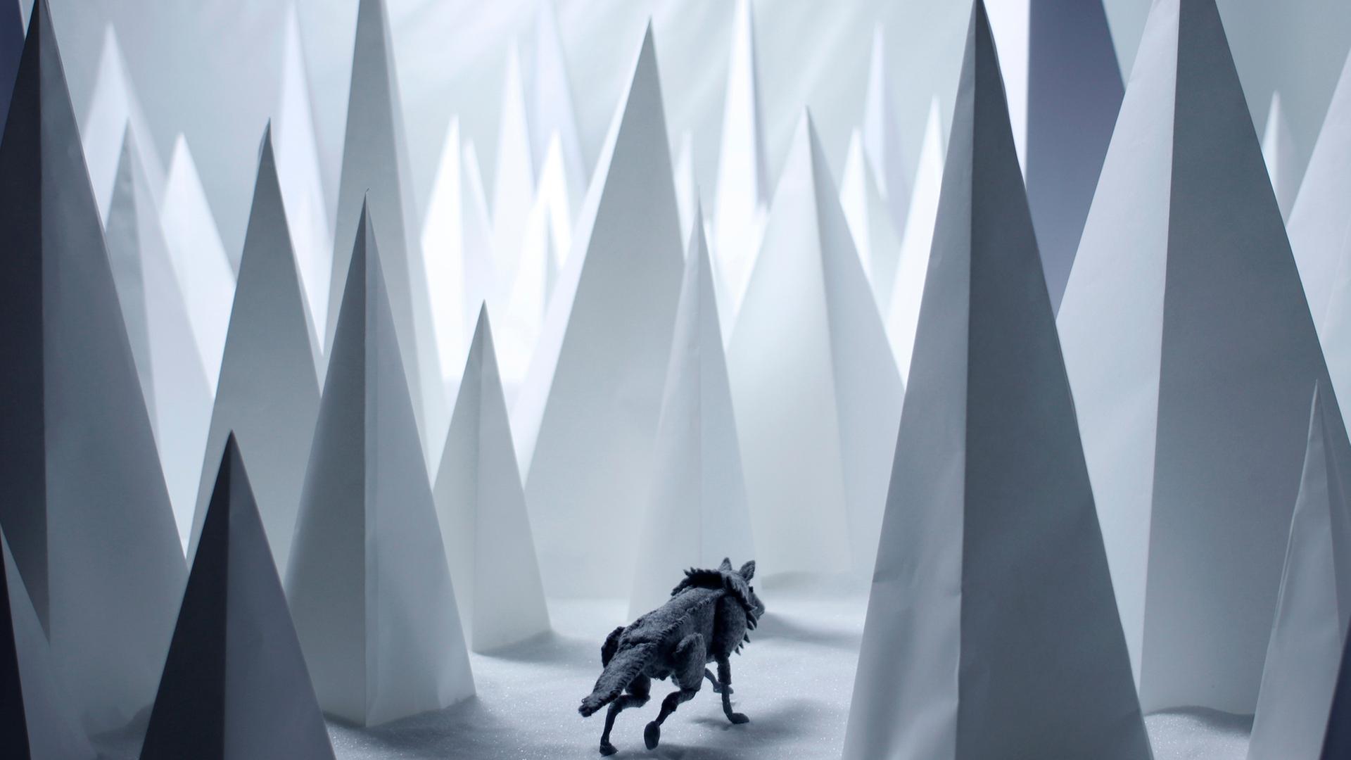 "Heile Welt": Ein Wolf aus Filz in einer aus Zucker und Papier geformten Landschaft, die einen verschneiten Wald darstellt.