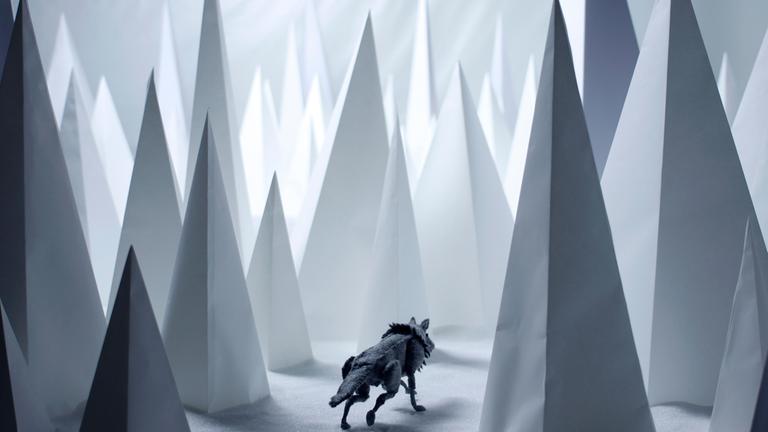 "Heile Welt": Ein Wolf aus Filz in einer aus Zucker und Papier geformten Landschaft, die einen verschneiten Wald darstellt.