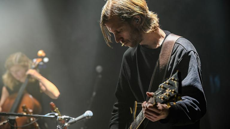 "Terra X: Musik - Große Gefühle": Ferdinand Kirner steht im Vordergrund und spielt Gitarre. Ella Rohwer sitzt seitlich dahinter und spielt Cello.