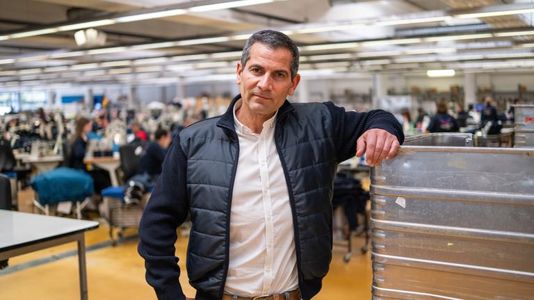 "Am Puls mit Mitri Sirin - Blaumacher-Republik Deutschland?": Mitri Sirin steht in einer Produktionshalle und schaut in die Kamera.