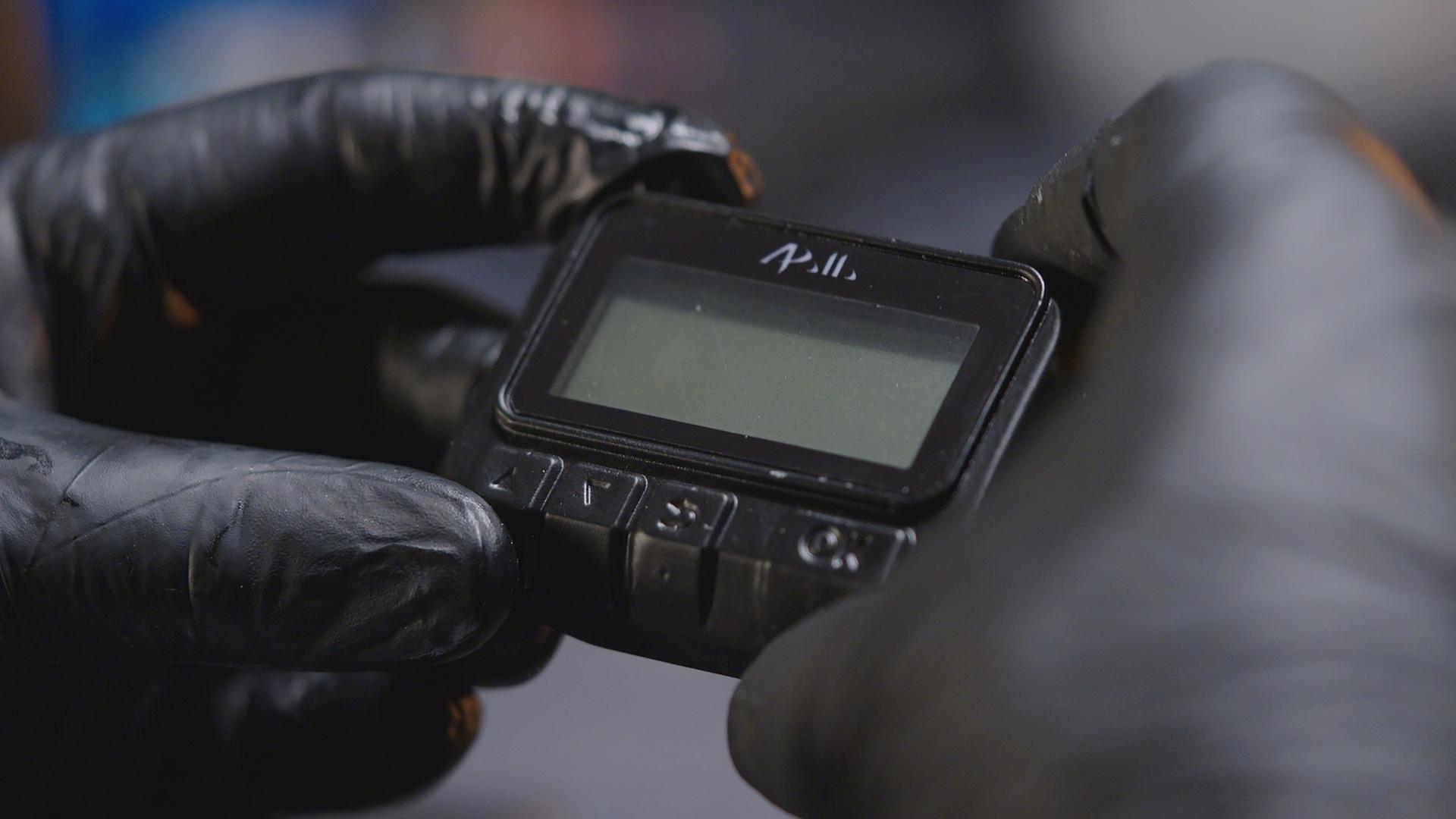 "frontal-Dokumentation: Operation Apollo - Die Pager Attacke des Mossad": Nachgestellte Szene, Nahaufnahme: Zwei Hände in Handschuhen halten einen Pager.