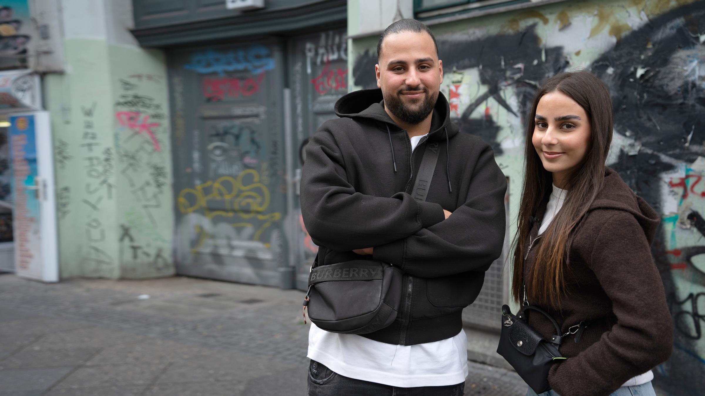 "ZDF.reportage: Türken in Deutschland - Zwischen den Kulturen": Melih Saydam und seine Schwester Melike stehen auf einer Straße in Berlin. Im Hintergrund ist eine Hauswand mit Graffiti.