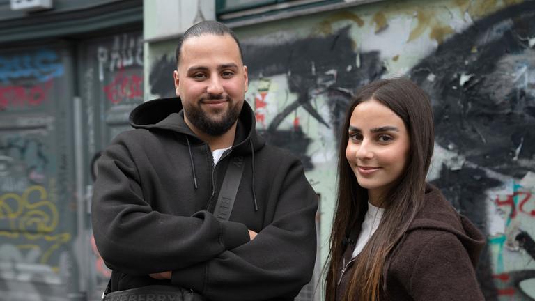"ZDF.reportage: Türken in Deutschland - Zwischen den Kulturen": Melih Saydam und seine Schwester Melike stehen auf einer Straße in Berlin. Im Hintergrund ist eine Hauswand mit Graffiti.