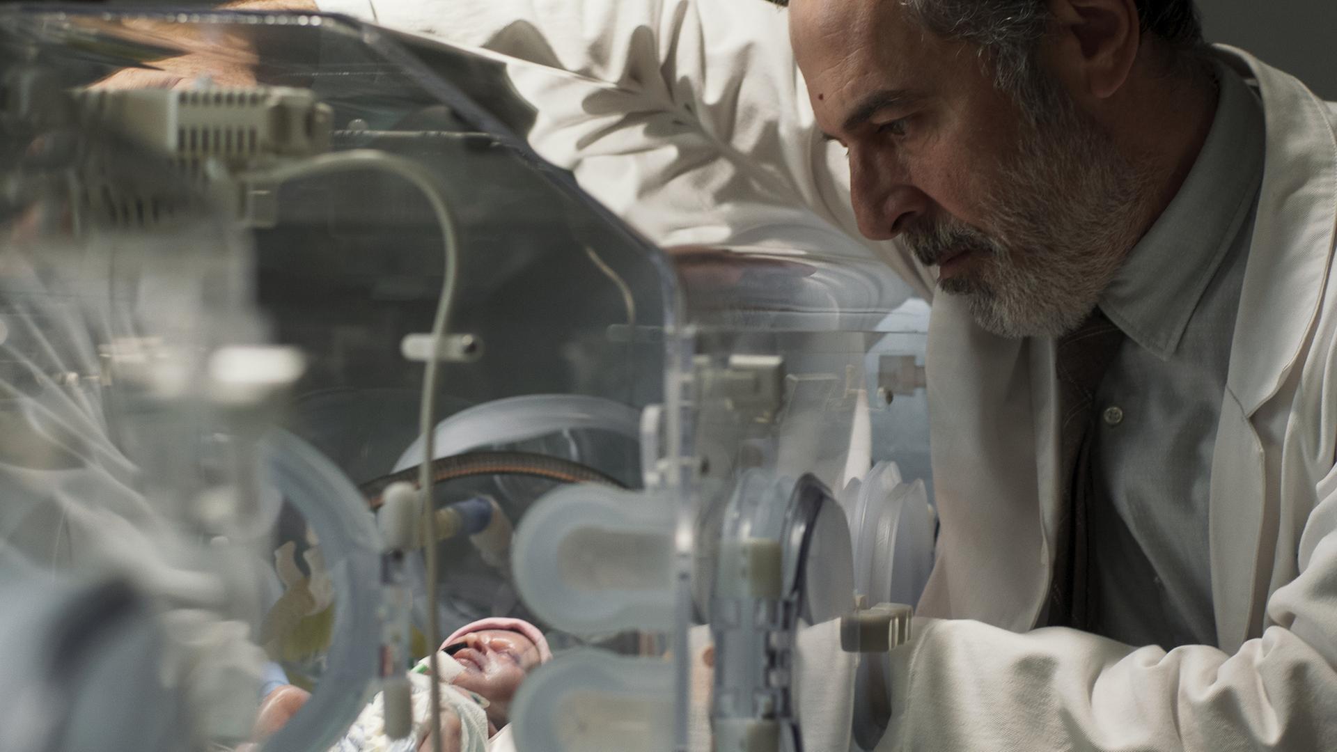 "Doktor Ballouz - Nur ein Wunder": Nahaufnahme: Dr. Ballouz (Merab Ninidze) blickt sorgenvoll auf ein neugeborenes Baby in einem Inkubator.