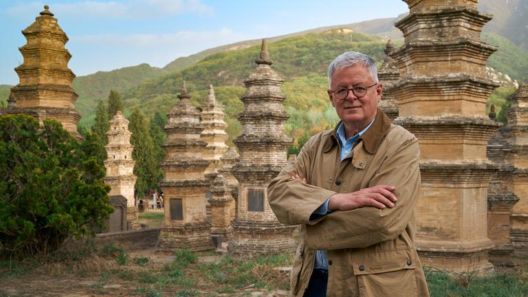 "Welten-Saga: Die Schätze Chinas": Moderator Christopher Clark steht mitten im Pagodenwald in der Nähe des Shaolin-