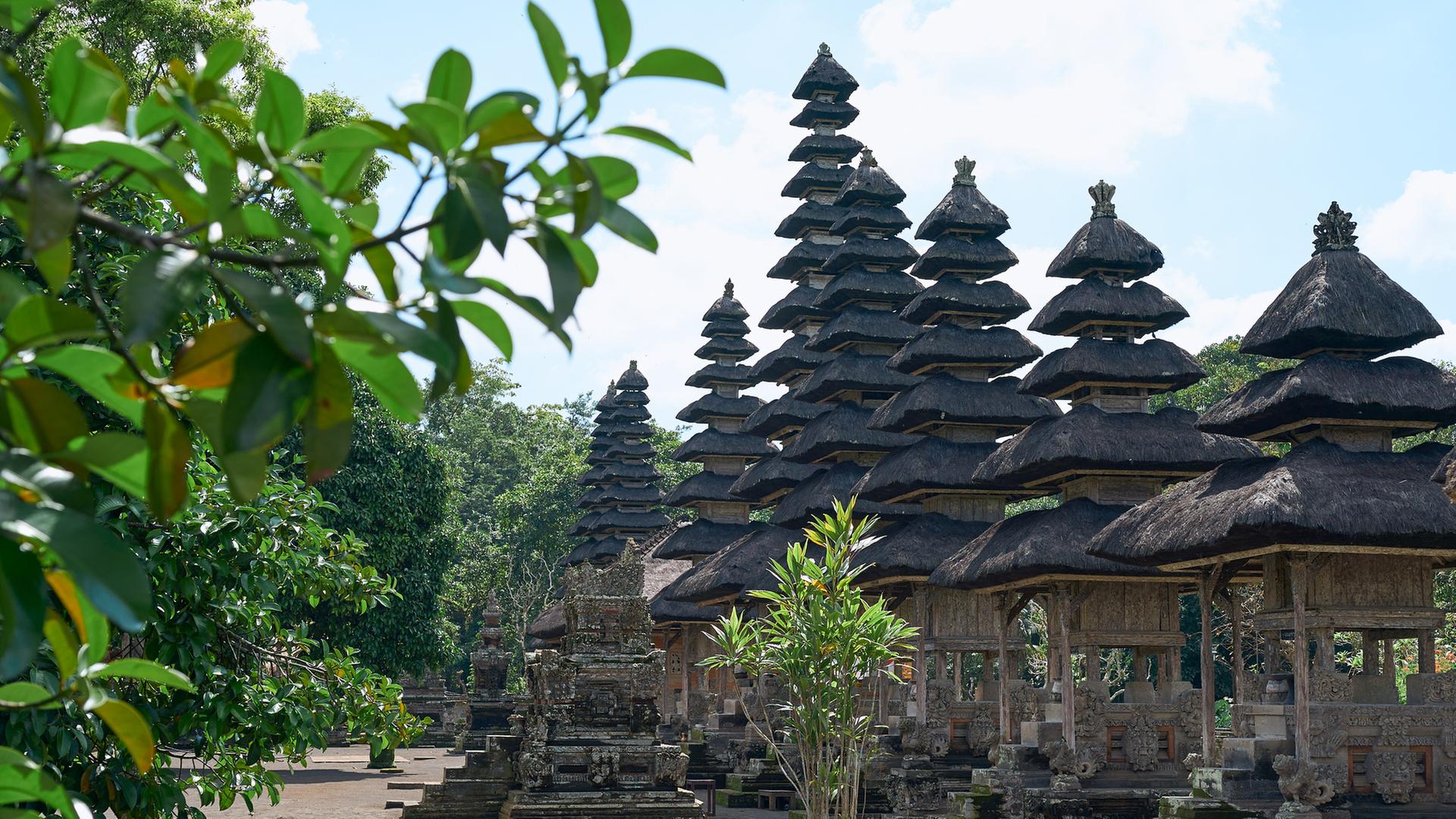 "Welten-Saga - Die Geschichte Indonesiens": Mehrere pagodenförmige Gebäude in unterschiedlicher Höhe stehen nebeneinander. Sie sind umgeben von grünen Bäumen.