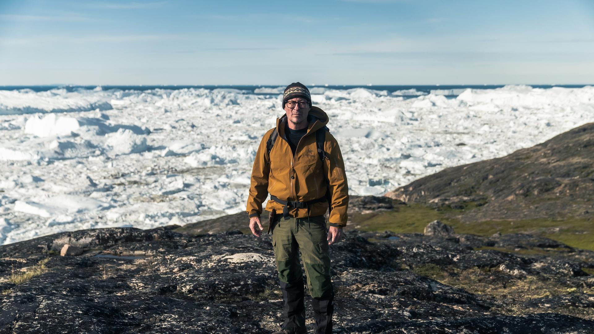 "Terra X: Vor der Eiszeit - Jagd nach dem ältesten Erbgut der Welt": Eske Willerslev ist Evolutionsgenetiker und steht bei einer Expedition auf einer eisfreien Fläche, hinter ihm erstreckt sich eine schnee- und eisbedeckte Landschaft.