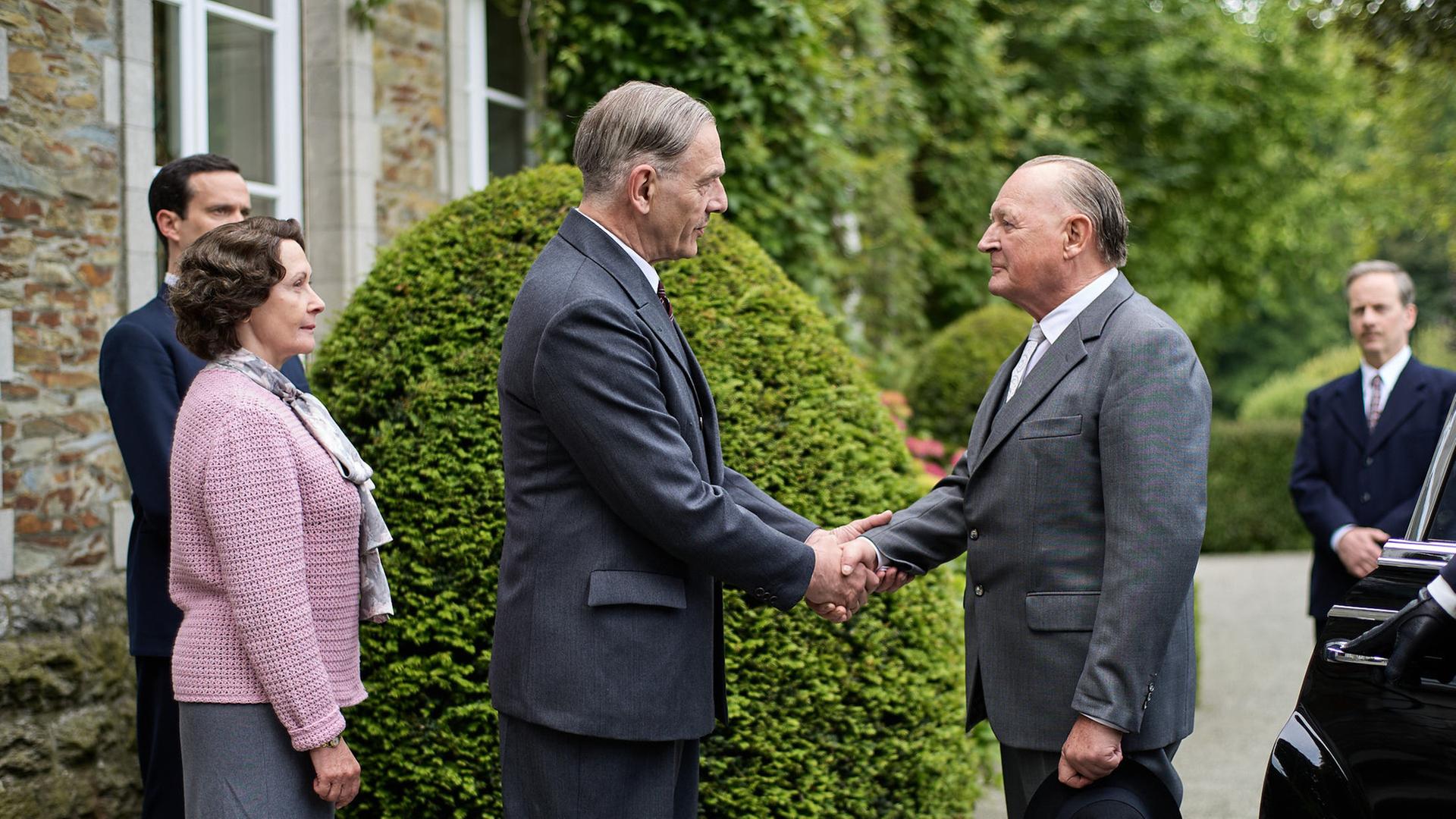 "An einem Tag im September": Charles de Gaulle (Jean-Yves Berteloot) und Konrad Adenauer (Burghart Klaußner) stehen sich vor dem Landhaus gegenüber und begrüßen sich mit einem Handschlag. Hinter de Gaulle stehen seine Frau Yvonne (Hélène Alexandridis) und sein Sohn Philippe (Pierre Lognay) und beobachten das Ganze. Günther Bachmann (Fabian Busch) steht etwas abseits hinter Adenauer und sieht ebenfalls zu.