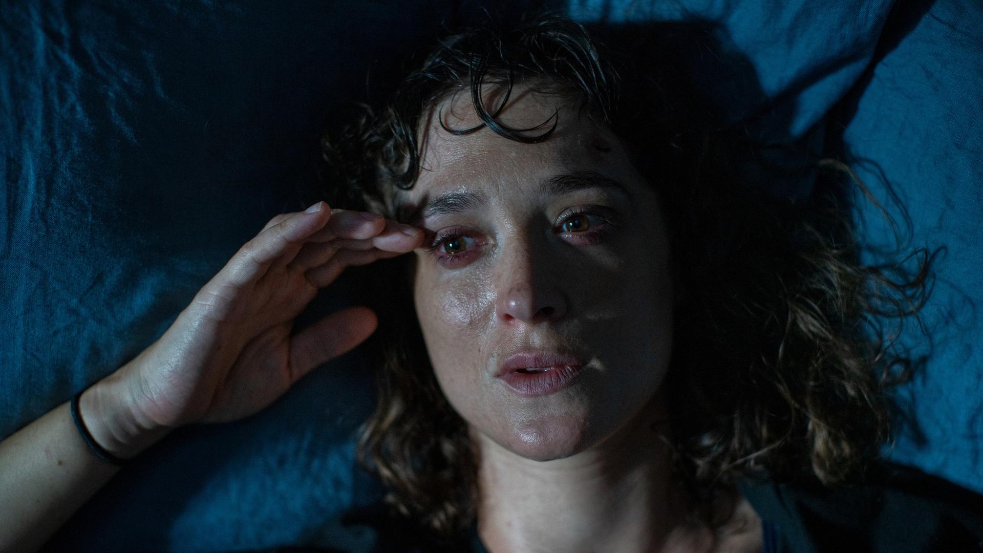 "Im Rausch": Blick von oben: Katja (Friederike Becht) liegt nachts betrunken in ihrem Bett und blickt seitlich an der Kamera vorbei. Sie sieht verschwitzt aus.