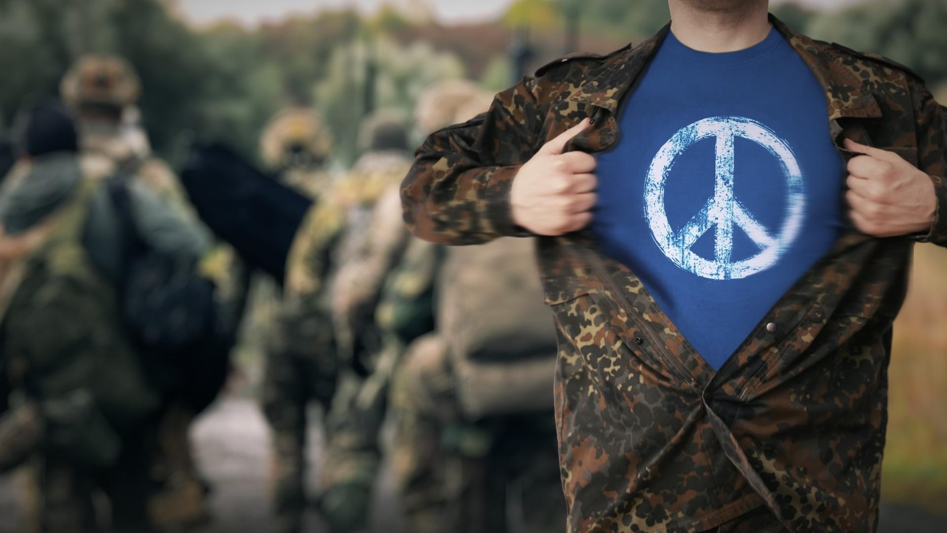  "Eine Frage des Gewissens": Ein Mann in Flecktarn reißt seine Jacke auf und trägt darunter ein T-Shirt mit einem Peace-Zeichen.