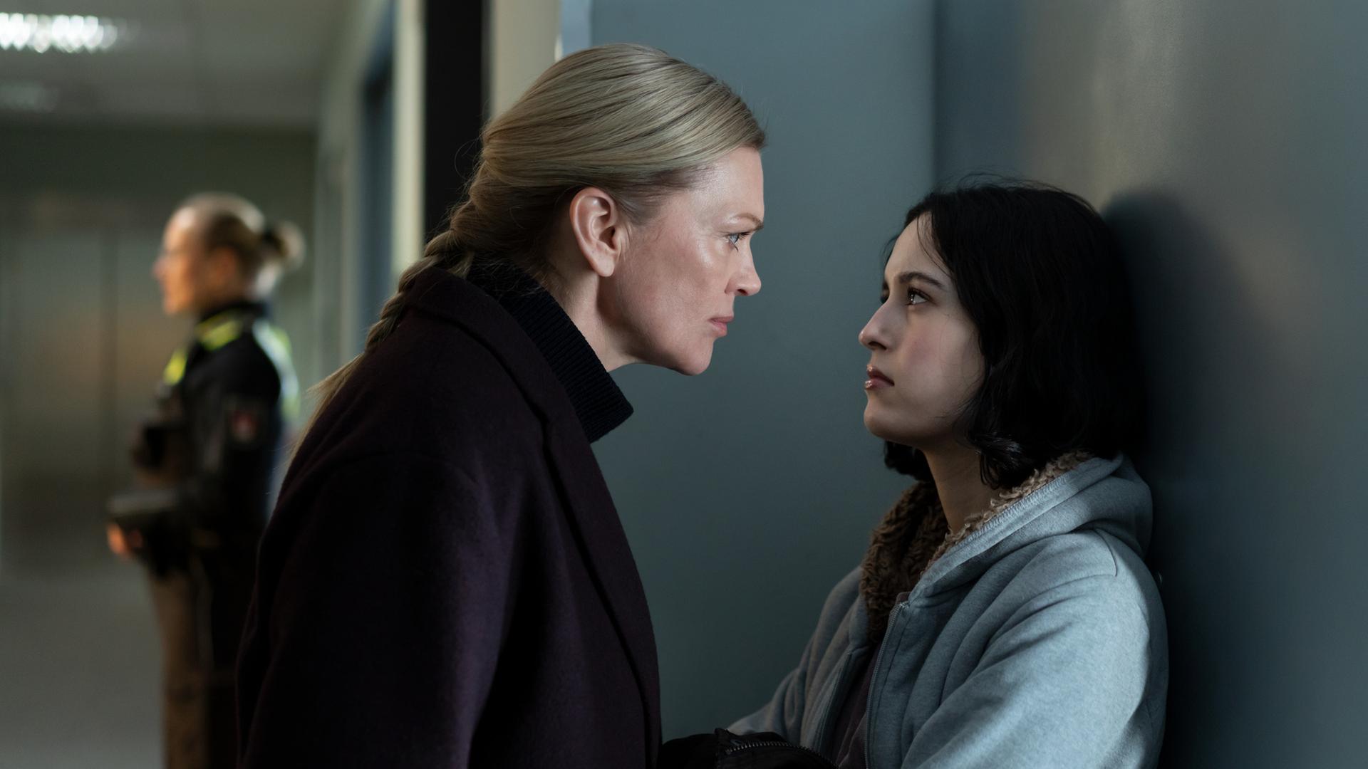 "Helen Dorn - Verdammte Familie": Helen Dorn (Anna Loos) spricht mit Tamara Jacobsen (Maya Lauterbach) auf einem Flur. Im Hintergrund steht eine Polizistin (Komparsin).