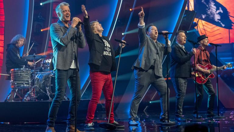 "Die Giovanni Zarrella Show - Party pur": Die Band "Die Prinzen" steht auf der Bühne der Giovanni Zarrella Show.  Fünf Bandmitglieder stehen in einer Reihe und singen in Standmikrofone. Im Hintergrund sitzt ein Schlagzeuger.