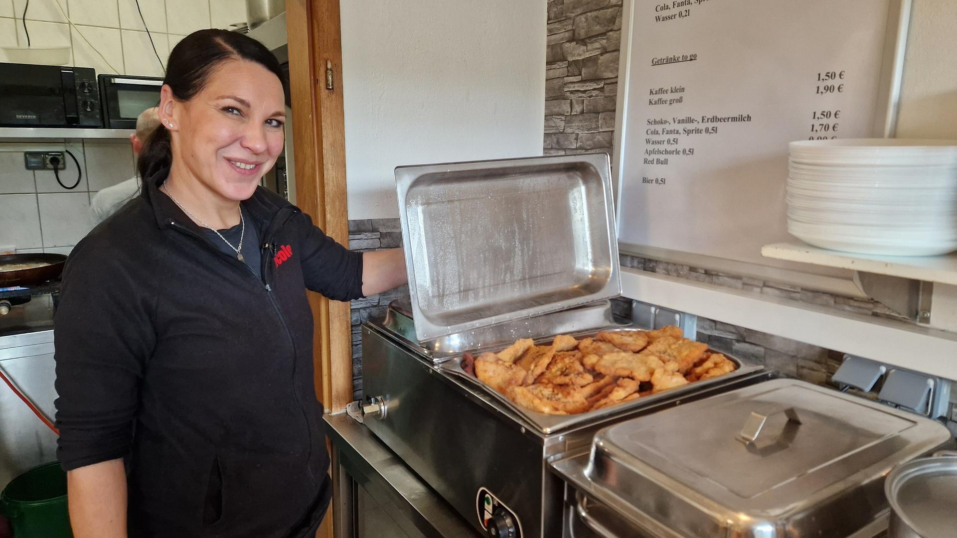 "ZDF.reportage: Essen - Hauptsache satt": Die Imbisschefin Nicole Dams steht vor der geöffneten Warmhaltebox mit fertigen Schnitzeln in der Küche. Sie schaut lächelnd in die Kamera.