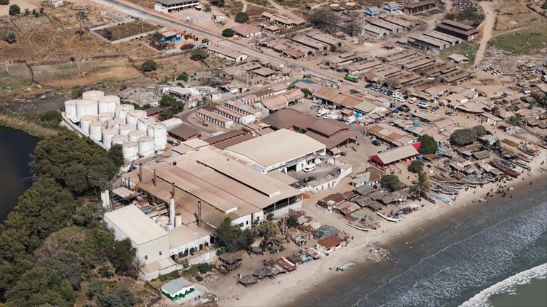 "Fischmehl - die dreckige Seite eines globalen Business": Drohnenaufnahme: Am Strand liegt ein Fabrikkomplex, die größte Fischmehlfabrik Gambias.