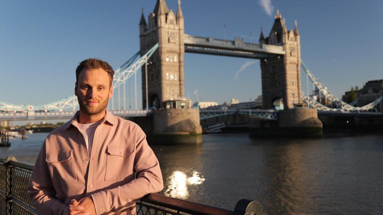 "Terra X: Weltstädte - London": Leon Windscheid steht am Ufer der Themse, hinter ihm führt die Tower Bridge über den Fluss.