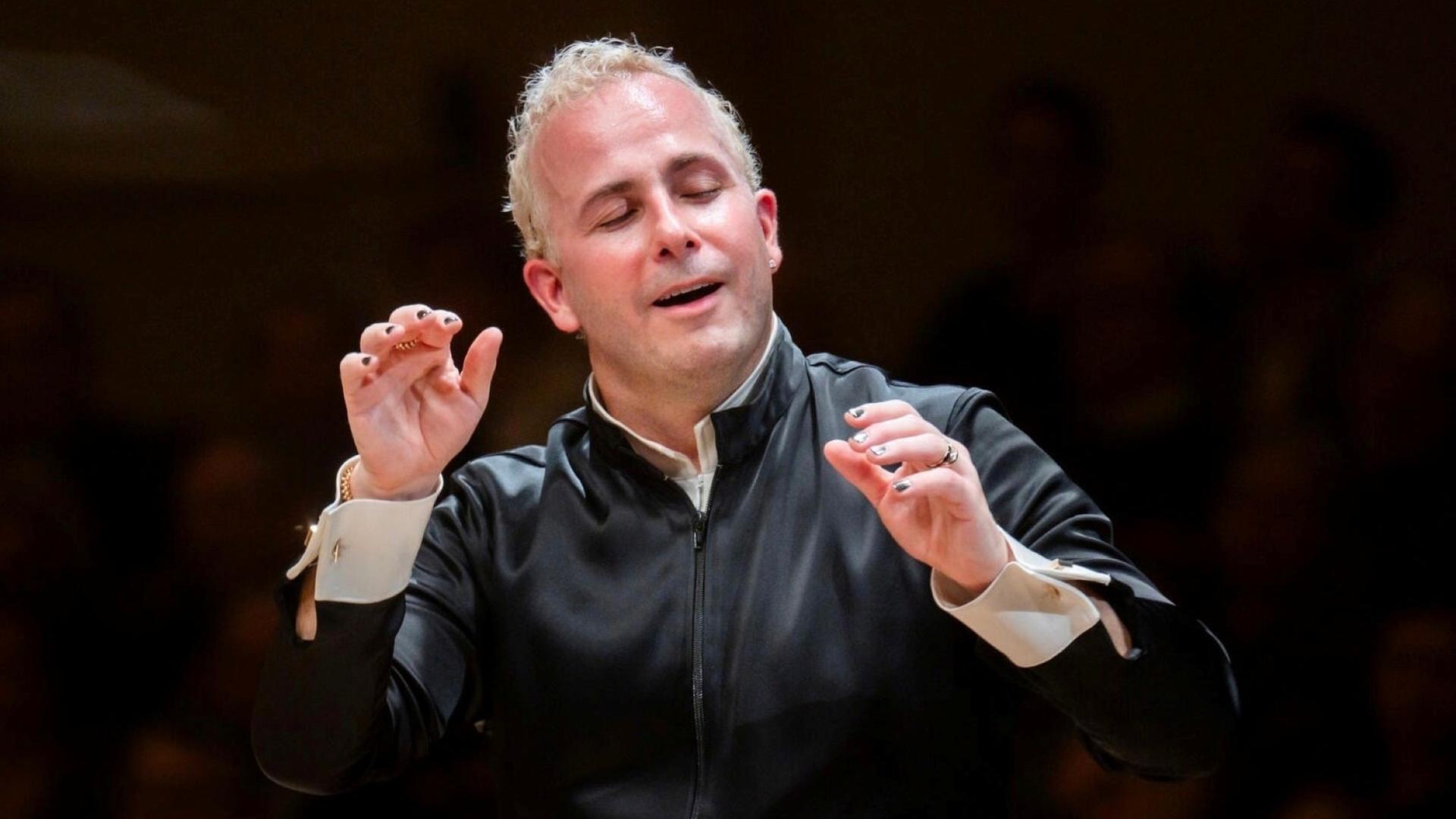 "Neujahrskonzert der Wiener Philharmoniker 2026": Der Dirigent Yannick Nézet-Séguin dirigiert mit beiden erhobenen Armen vor schwarzem Hintergrund. Er dirigiert nur mit den Händen und hat die Augen, wie beseelt, geschlossen.