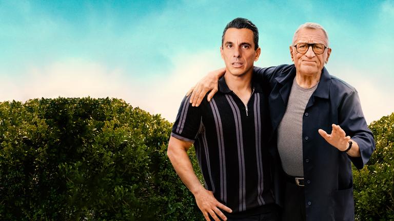  "Und dann kam Dad": Sebastian (Sebastian Maniscalco) und sein Vater Salvo (Robert De Niro) stehen nebeneinander vor einer Hecke und blicken skeptisch nach vorne. Salvo hat einen Arm um seinen Sohn gelegt und macht eine abweisende Geste.