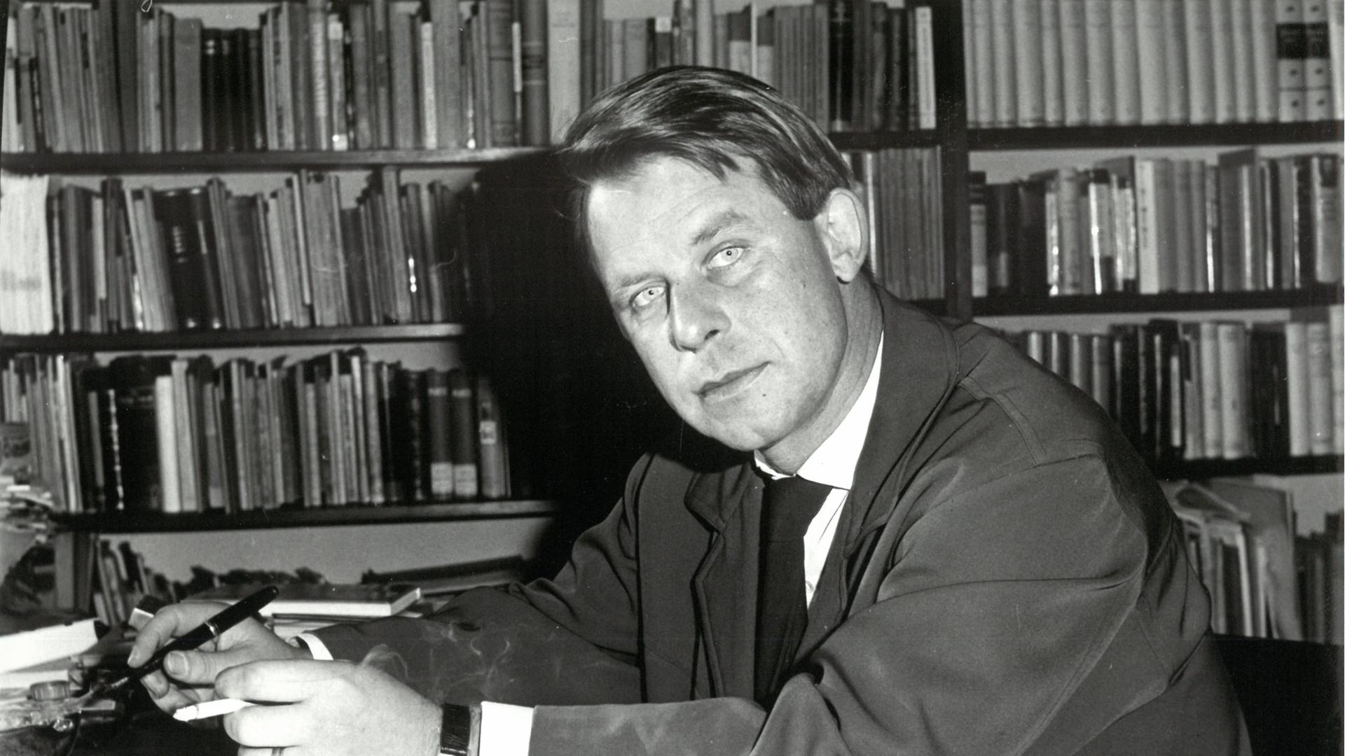 "Siegfried Lenz und die Kraft des Gewissens": Der junge Siegfried Lenz sitzt vor einer Bücherwand am Schreibtisch (s/w).