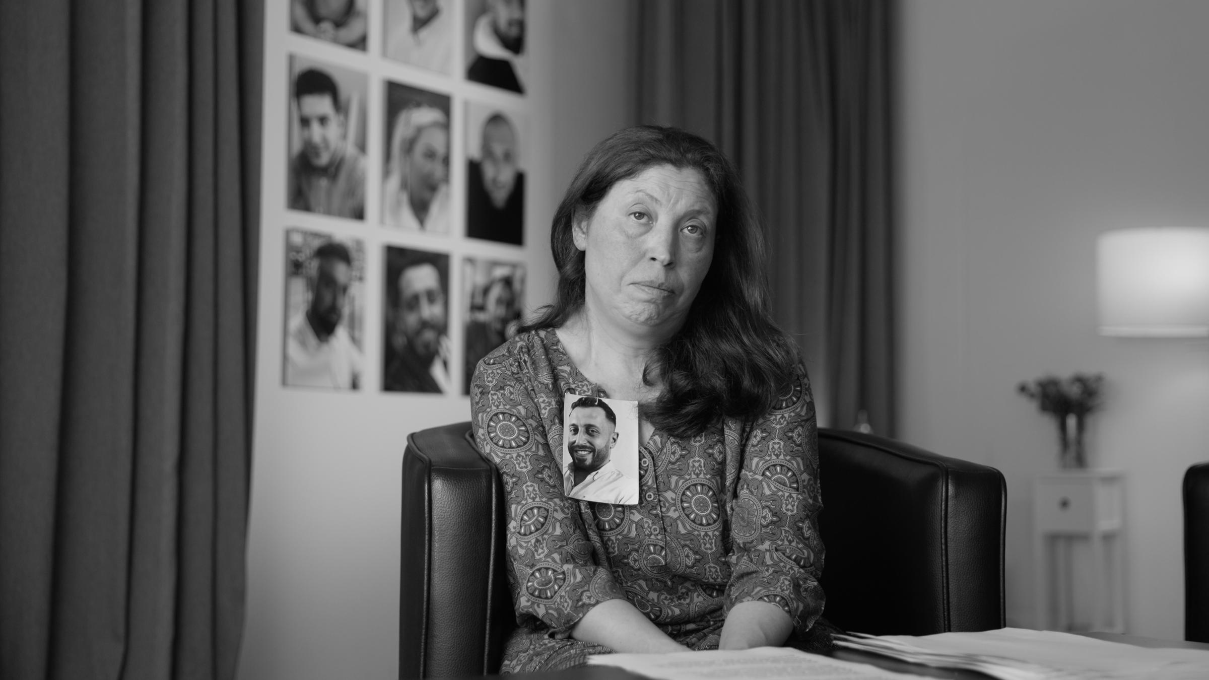 "Das Deutsche Volk": Frau blickt direkt in die Kamera. An ihrem Revers ist das Foto eines jungen Mannes befestigt.