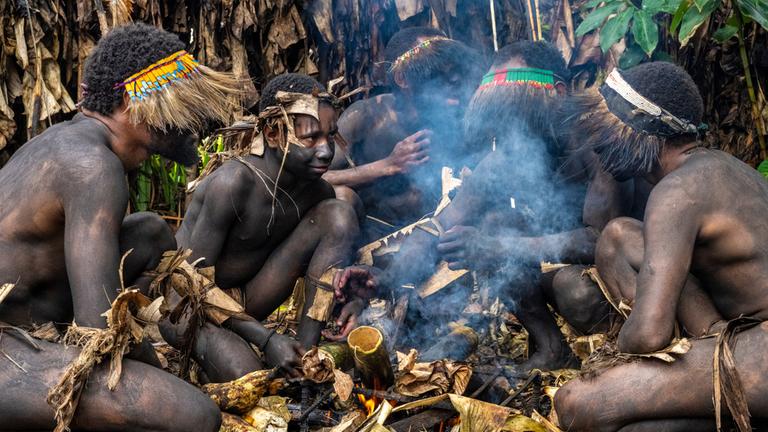 "Terra X: Tabu - Wahrheit und Mythos": Bei Dreharbeiten in Goroko in Papua Neu-Guinea: Fünf Asaro-Krieger sitzen am Lagerfeuer.